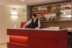 Un uomo in piedi dietro un bancone in un bar di Hotel Airmotel a Mestre