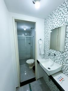 a bathroom with a sink and a toilet and a mirror at Guarapousada in Guarapari