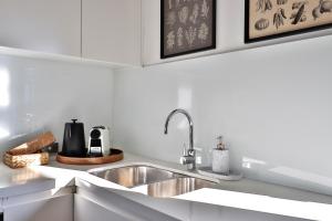 una cocina con fregadero de acero inoxidable y armarios blancos en Lumière Urban Hideaway-Split Level ·Views ·Parking en Sídney