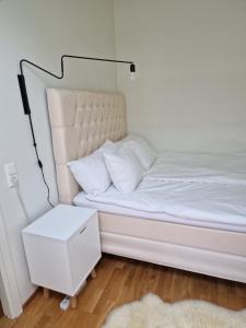 a white bed with a white night stand next to it at Gothenburg City Apartment in Gothenburg