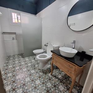 ein Badezimmer mit einem Waschbecken, einem WC und einem Spiegel in der Unterkunft Posta Belgrano in Mendoza