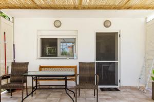 einen Tisch und Stühle auf einer Terrasse mit einem Fenster in der Unterkunft Garden Rooms in Fanárion