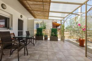 eine Terrasse mit einem Tisch, Stühlen und Pflanzen in der Unterkunft Garden Rooms in Fanárion