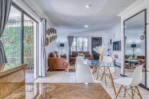 ein Wohnzimmer mit einem Glastisch und weißen Stühlen in der Unterkunft The Cottage-1 Bed-pool-bbq-fibre-solar-samrand in Centurion