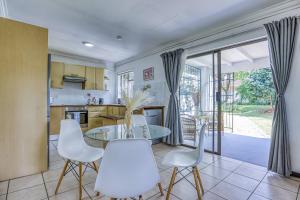 a kitchen with a glass table and white chairs at The Cottage-1 Bed-pool-bbq-fibre-solar-samrand in Centurion