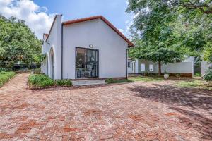 eine gemauerte Auffahrt vor einem weißen Haus in der Unterkunft The Cottage-1 Bed-pool-bbq-fibre-solar-samrand in Centurion