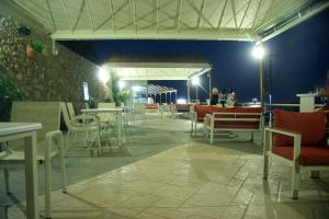 a restaurant with white tables and chairs and a wall at Santa Marina Apartments in Rodakino