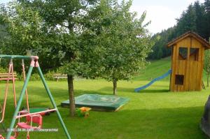 um parque infantil com uma árvore e um escorrega e uma estrutura de jogos em Mosertonihof em Elzach