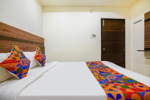 a bedroom with a bed with a colorful blanket on it at FabHotel Raj Vihar Residency in Vijayawāda