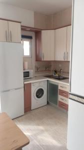 cocina con armarios blancos, lavadora y secadora en SERVILUX 4, en Torremolinos