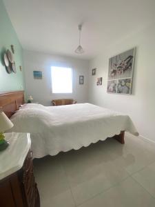 ein Schlafzimmer mit einem Bett mit einer weißen Tagesdecke in der Unterkunft maison au calme in La Tourlandry