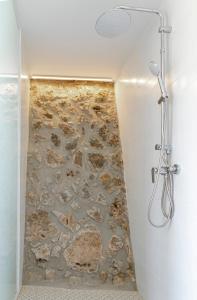 a shower in a bathroom with a stone wall at Finca de l’Anglès. Casa Mistral in Potríes