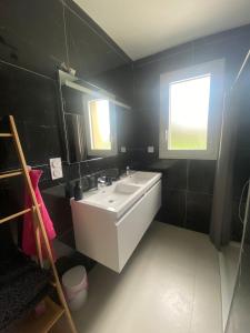 baño con lavabo blanco y paredes negras en maison au calme, en La Tourlandry