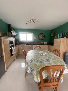 eine Küche mit einem Tisch und Stühlen sowie grünen Wänden in der Unterkunft maison au calme in La Tourlandry