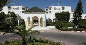 a white building with a courtyard with trees and plants at El Mouradi Palm Marina - Couple et Famille uniquement in Port El Kantaoui