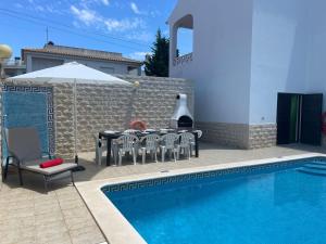 a swimming pool with a table and chairs next to a house at Villa Lucia, Olhos D'Agua, Albufeira in Albufeira