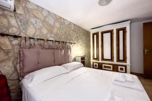 a bedroom with a white bed with a stone wall at [Eleganza Rustica In Villa] A 5 minuti dal mare in Tonnara di Bonagia