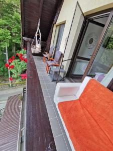 un porche con un banco y sillas en una casa en Apartament Kalinderu K1 Bușteni, en Buşteni