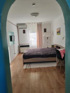 a bedroom with a bed and a desk and a window at Skylark Relax Apartman in Szeged
