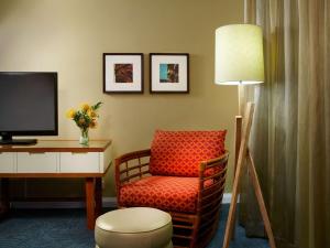 a room with a chair and a desk with a television at Oasis Hotel Waikiki in Honolulu