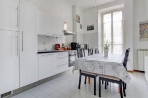 ローマにあるホリデー サニー ローマ B&Bの白いキャビネット、テーブルと椅子付きのキッチンが備わります。