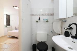 a white bathroom with a toilet and a sink at קו ראשון לים in Netanya