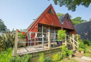een houten huis met een veranda en een terras bij Chalet One in Deal