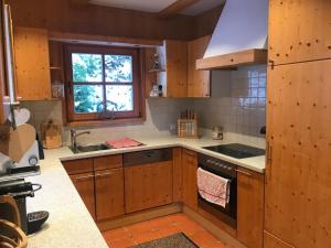 eine Küche mit Holzschränken, einem Waschbecken und einem Fenster in der Unterkunft Chalet Sodamin Alpin mit Wellness in Hohentauern