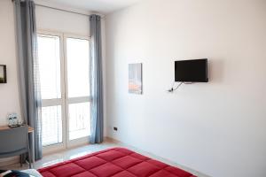 sala de estar con cama roja y ventana en A casa di Vito, en Mazara del Vallo