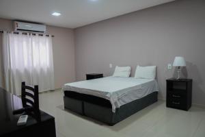 a white bedroom with a bed and a window at Amazônia Palacce Hotel in Marabá