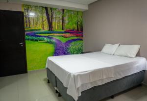 1 dormitorio con 1 cama con una pintura en la pared en Amazônia Palacce Hotel, en Marabá