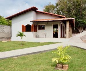 una pequeña casa blanca con una palmera en el patio en Chalés Tucano Praia da Pipa - Natureza, Conforto, Tranquilidade en Pipa