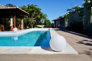 uma piscina com uma bola branca ao lado de uma casa em Chalés Tucano Praia da Pipa - Natureza, Conforto, Tranquilidade em Pipa