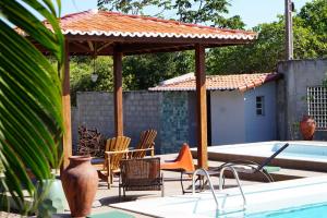 eine Terrasse mit Stühlen und einem Pavillon neben einem Pool in der Unterkunft Chalés Tucano Praia da Pipa - Natureza, Conforto, Tranquilidade in Pipa