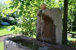 Una fuente de piedra con un pájaro encima. en Ferienhaus Wieke - eine Oase der Erholung, en Wiesmoor