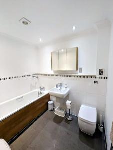 a bathroom with a sink and a toilet and a tub at SoHot Stays-Garden Apt-Free Parking Ground Flr in Kent