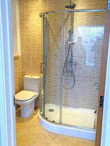 a bathroom with a toilet and a glass shower at SoHot Stays-Garden Apt-Free Parking Ground Flr in Kent