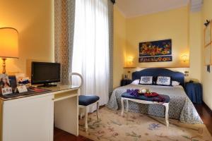 馬格拉的住宿－卡薩梔子花別墅酒店，一间卧室配有一张床和一张书桌及电视