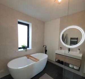 La salle de bains est pourvue d'une grande baignoire blanche et d'un miroir. dans l'établissement Croft Cottage by Mourne Homestays, à Glasdrumman 13 autres photos