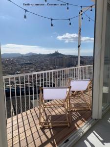 a balcony with two chairs and a view of a city at LaFrenchCasa Clandestina in Marseille