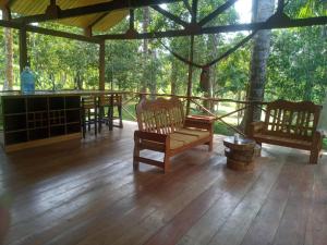un porche con sillas, mesa y árboles en Eco Villa Uaturi, en Iquitos