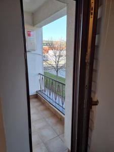 eine Tür zu einem Balkon mit Blick auf einen Baum in der Unterkunft Studio apartman Šapudl in Vukovar