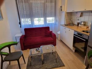 uma sala de estar com um sofá vermelho numa cozinha em Studio apartman Šapudl em Vukovar
