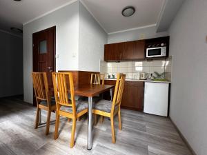 kuchnia z drewnianym stołem i krzesłami w pokoju w obiekcie Apartament Serwis w Krakowie