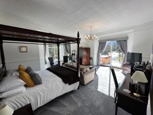 a large bedroom with a large bed and a television at Craig-y-Dderwen Riverside Hotel in Betws-y-coed