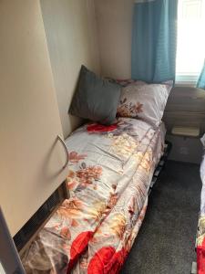 um pequeno quarto com uma cama com colcha floral em St Marys Light house, Caravan Rentals em Whitley Bay
