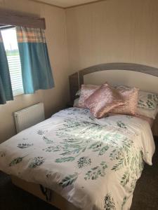 uma cama com um edredão branco e almofadas em St Marys Light house, Caravan Rentals em Whitley Bay