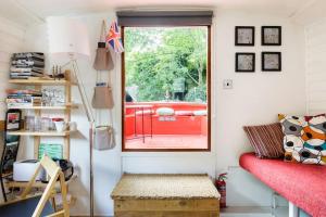 a small room with a red couch and a window at Slash Arts houseboat on secluded mooring in central London in London