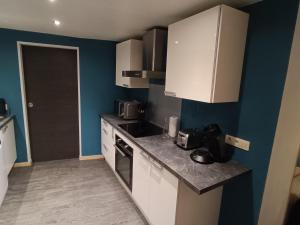 a kitchen with white appliances and blue walls at Maison 4 chambres proche Etretat in Les Loges