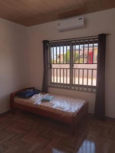een bed in een kamer met een groot raam bij Serenity Divine vastgoed Beheer in Paramaribo